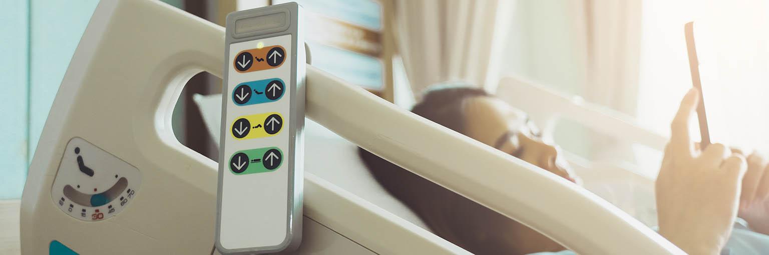 Hospital bed remote control hanging on the bed rail with woman