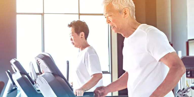 two asian senior citizen running treadmill